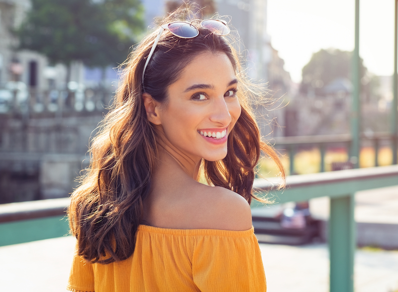 Young woman looking back over her shoulder as she walks away
