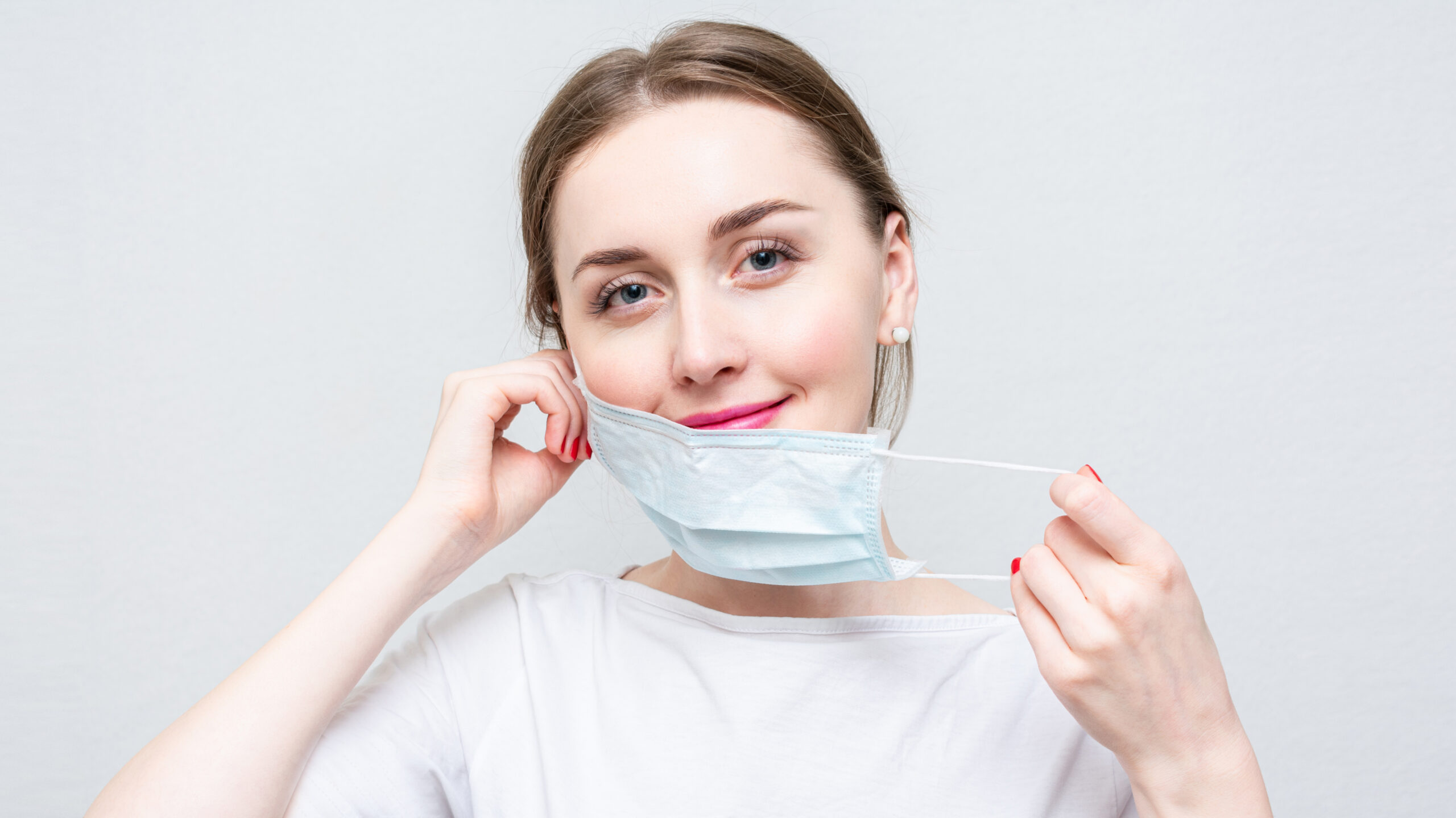 Beautiful brunette woman placing a mask on her face.