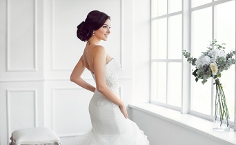 Happy bride posing by the window on her wedding day
