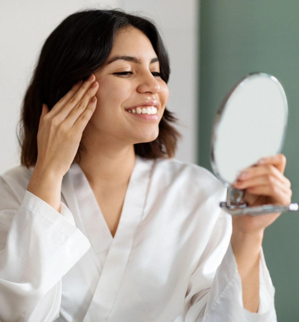 young woman happy with her clear skin looking in the mirror