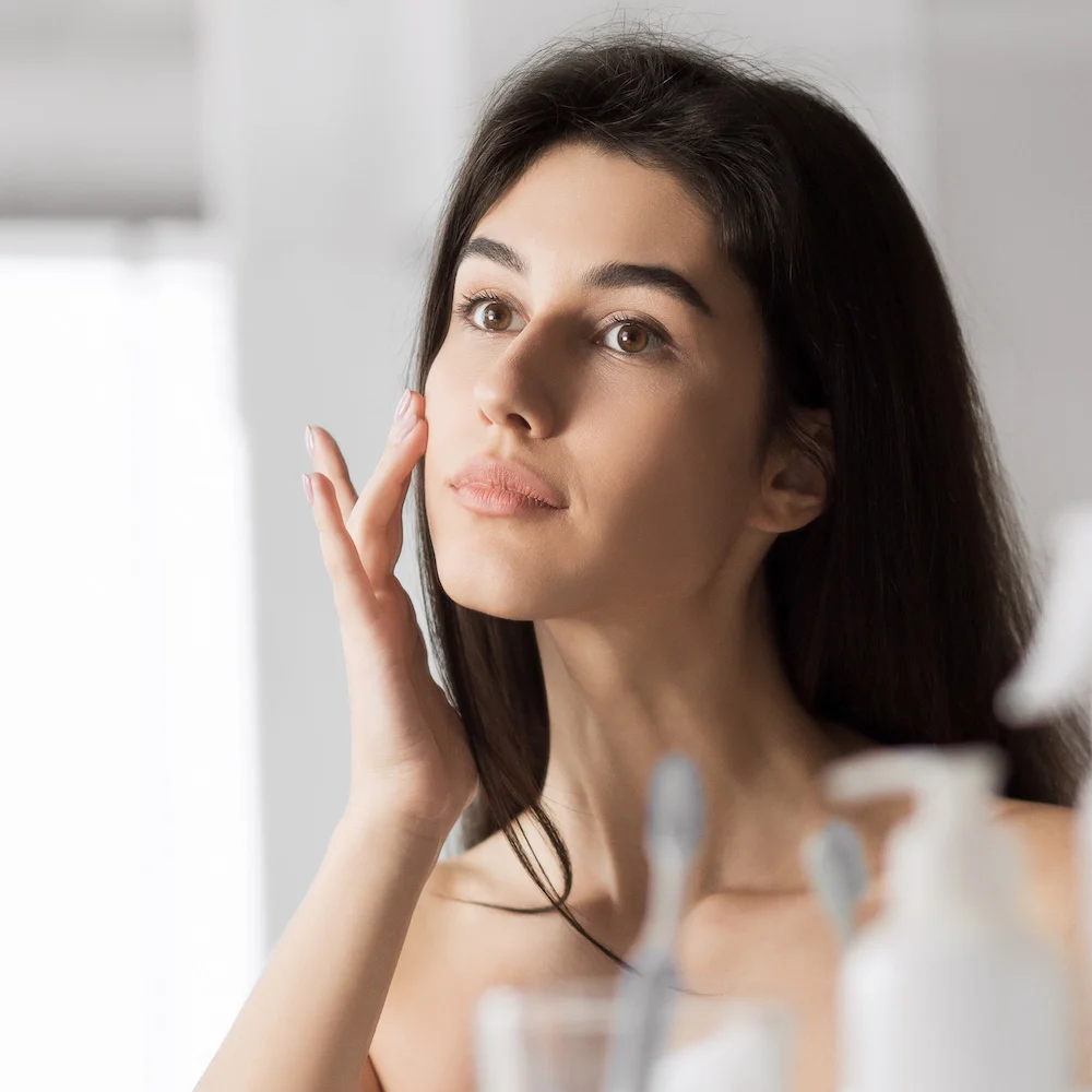 woman looking in the mirror at her skin