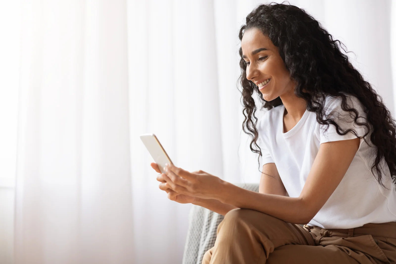 Beautiful woman at home applying for financing on her phone