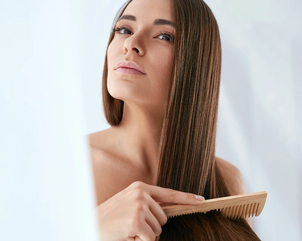 woman combing through long healthy hair