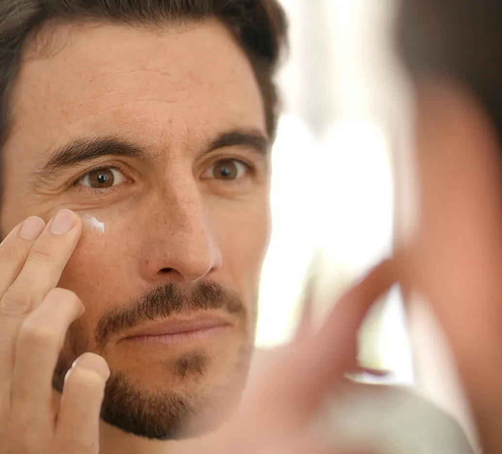 mature man applying skincare product under eye