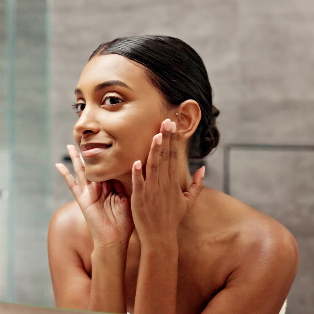30s woman looking in the mirror admiring her smooth skin