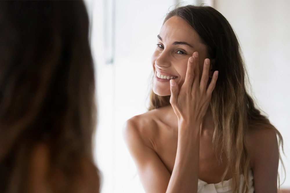 woman looking at her skin in the mirror